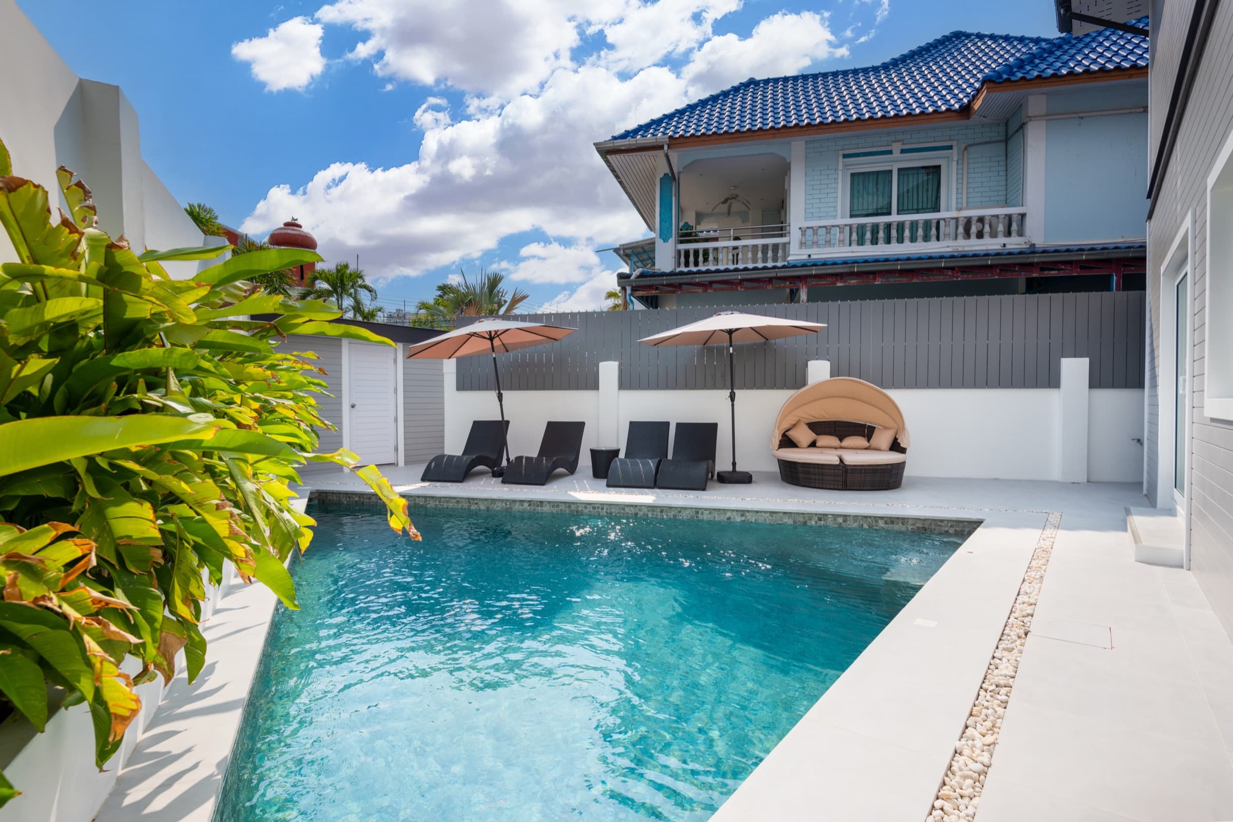 The Cerulean wing's saltwater pool — sun loungers, daybed cabana with umbrellas, and the blue-tile-roofed wing in the background.