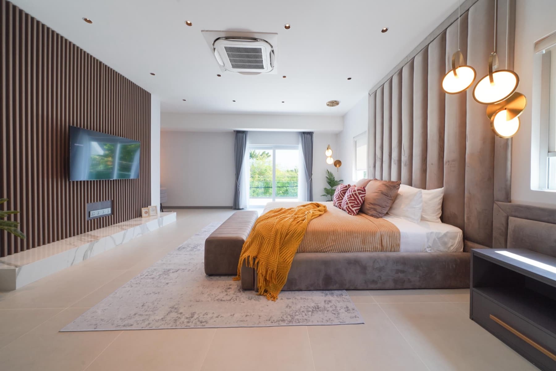 ห้องนอนใหญ่ชั้นบนของโซน Indigo ผนังไม้ระแนงและผ้าคลุมเตียงสีเหลือง